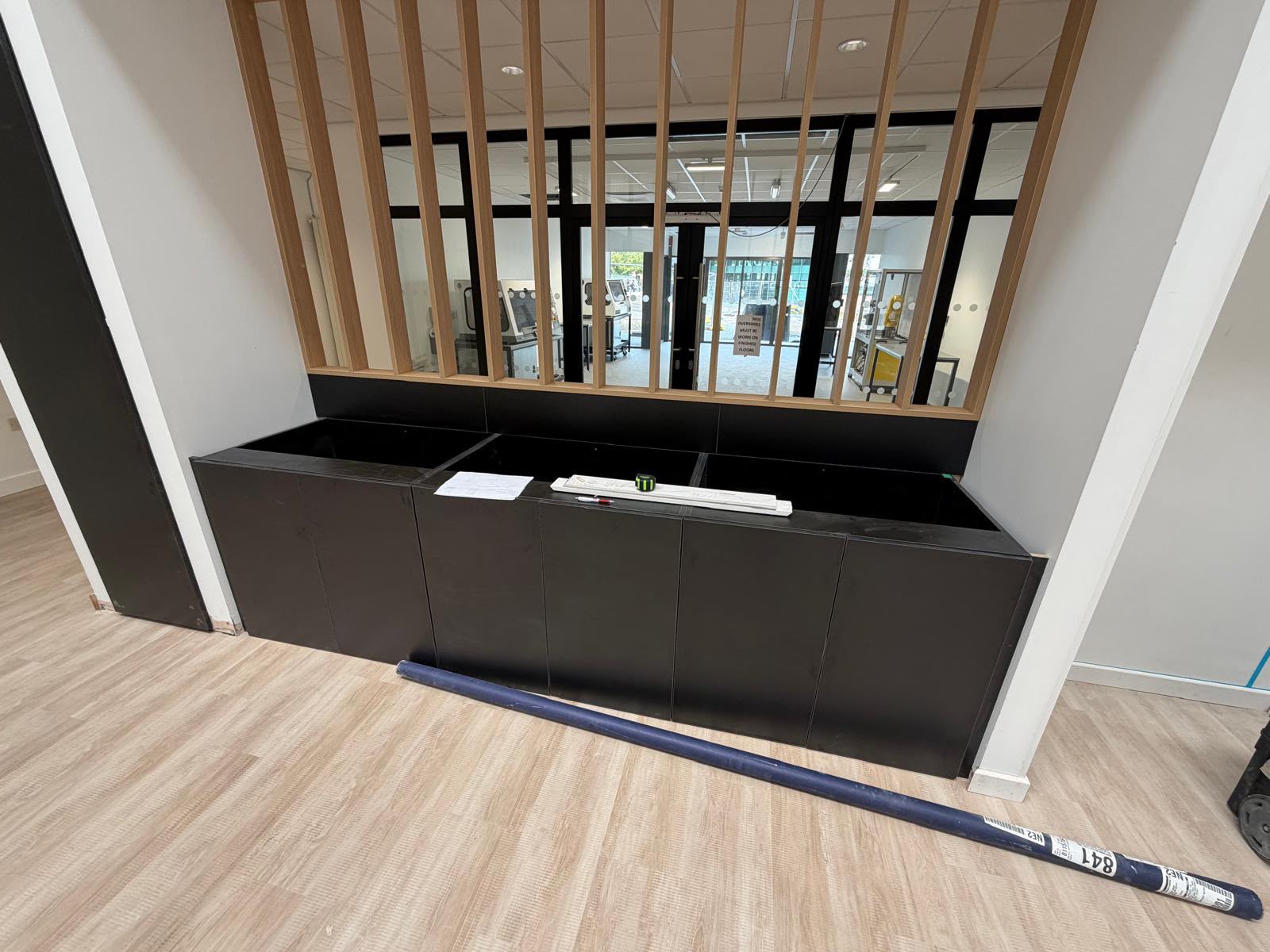 Black fitted storage with a full-height timber screen in a commercial interior
