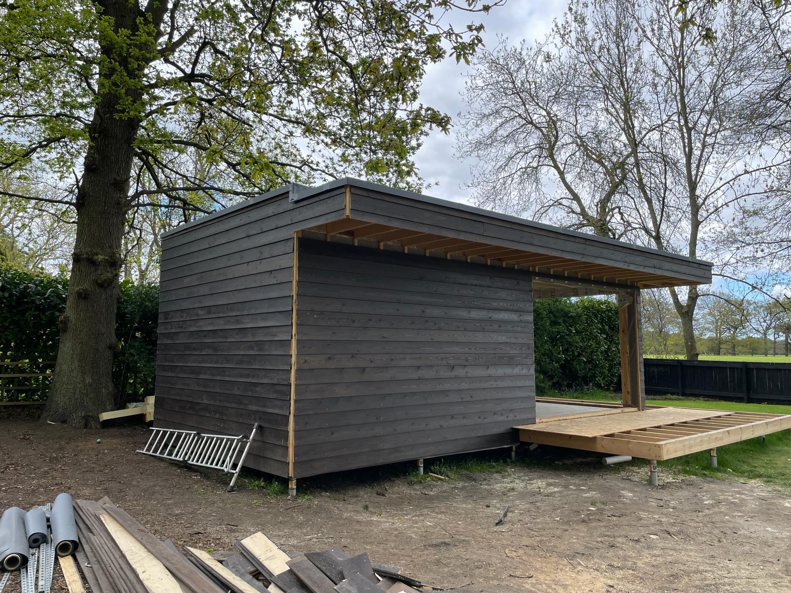 Dark timber cladding and projecting roof detail during garden room construction
