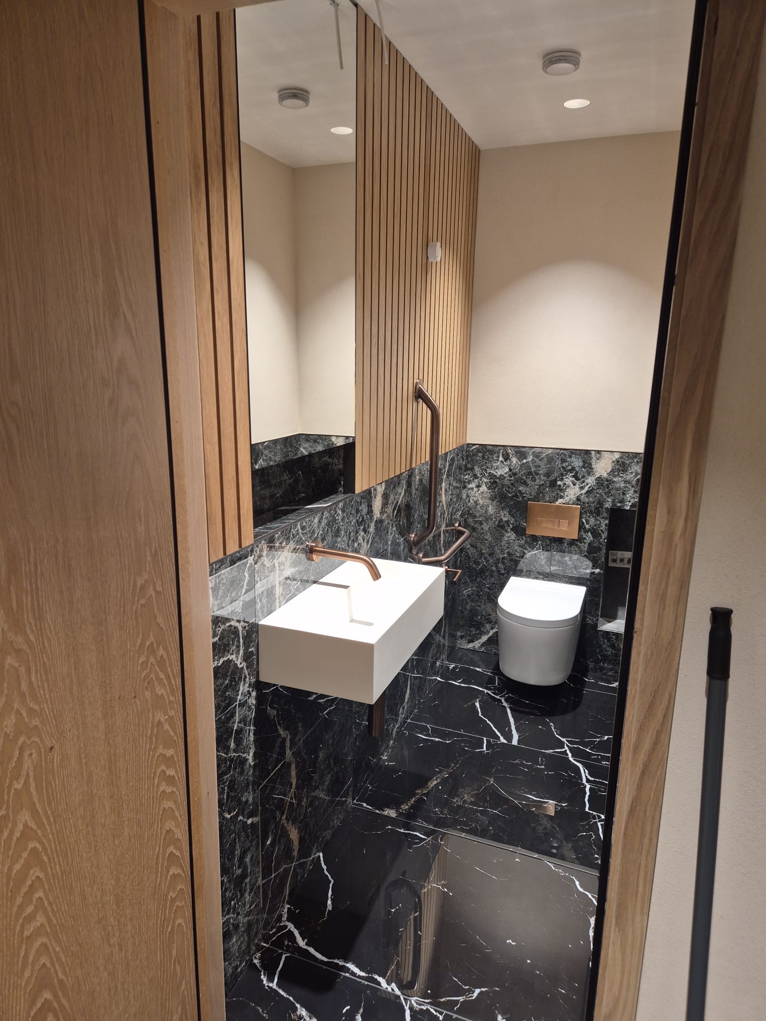 Oak doors, frames and slatted timber detailing in a specialist bathroom interior